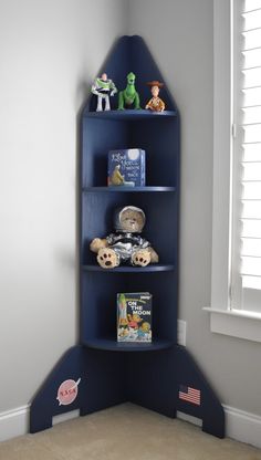 a blue book shelf in the corner of a child's room with toys on it