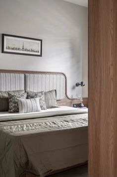 a bed sitting in a bedroom next to a wooden door and framed pictures on the wall