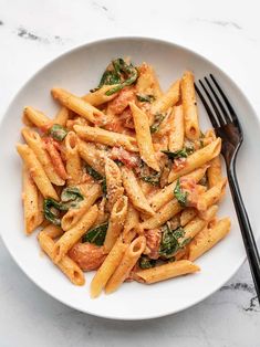 a white bowl filled with pasta and spinach