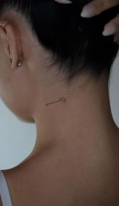 a woman with a small tattoo on her neck and behind her ear is the word love