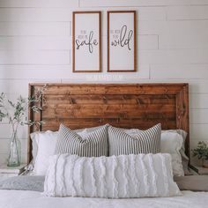 a bed with two framed pictures above it and pillows on the headboard, in front of a white shiplap wall