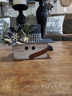 a wooden table topped with a white box filled with christmas decorations on top of it