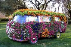 an old vw bus covered in flowers and plants