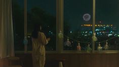 a woman standing in front of a window looking out at the city lights and fireworks