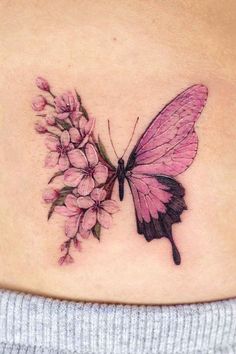 a woman's stomach with a butterfly and flowers tattoo on the back of her belly