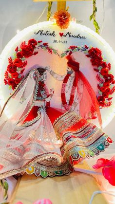 a cake with two brides on it and red flowers around the edges, in front of a white background