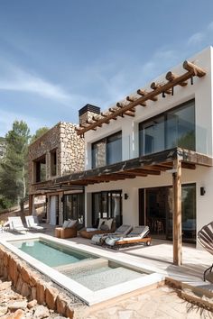 a large white house with a pool in front of it and an outdoor lounge area