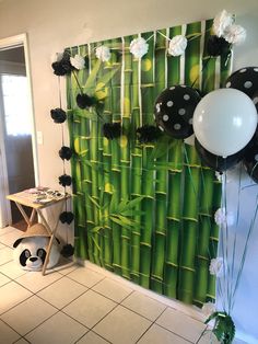 a panda bear balloon and some balloons in front of a bamboo wall with black and white decorations