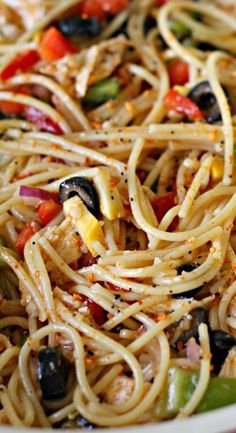 pasta with olives, peppers and chicken in a white bowl on a wooden table