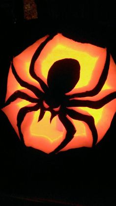 a pumpkin with a spider carved into it's center and its shadow on the top