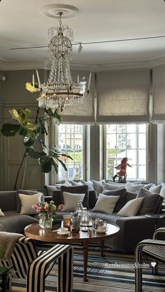 a living room filled with lots of furniture and a chandelier hanging from the ceiling