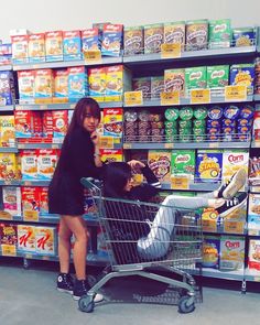 a woman standing next to a shopping cart talking on a cell phone in a grocery store