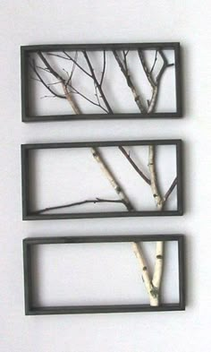 three metal frames with trees in them on a white surface and one is hanging from the wall