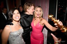 three women pose with an award in front of a group of people at a party