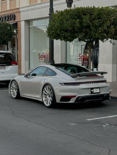 a silver sports car parked in front of a store