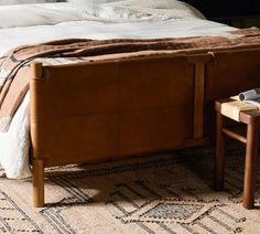 a bed with a brown leather headboard and foot board sitting on top of a rug