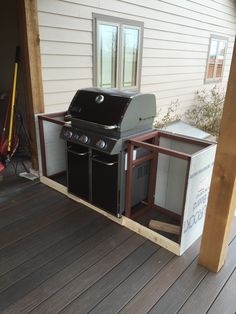 an outdoor bbq grill on a deck with the door open to reveal it's storage area