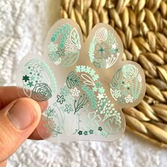 a person holding up a sticker with flowers on it in front of a basket