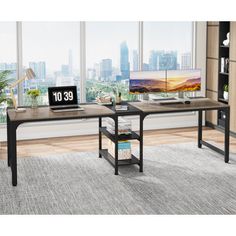 two computer desks sitting on top of a rug in front of a large window