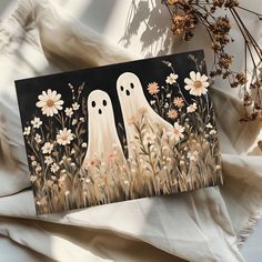 two white ghost standing in the grass with daisies