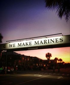 a sign that says we make marines over a street with palm trees in the background