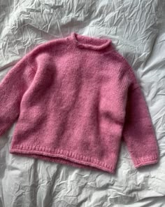 a pink sweater laying on top of a bed