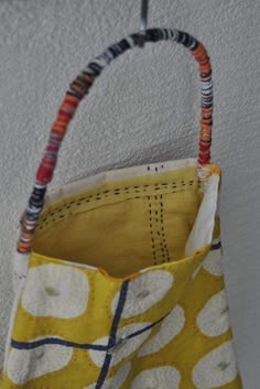 a handbag hanging from the ceiling in a room with white walls and flooring