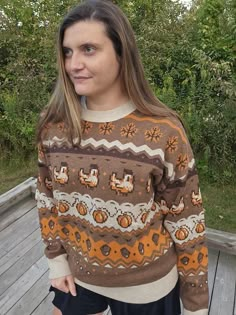 a woman standing on a wooden deck wearing a sweater that has an ugly pattern and is looking at the camera