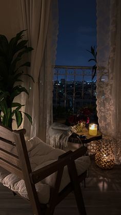 a chair sitting in front of a window next to a potted plant and candle