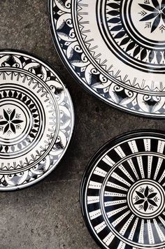 three black and white plates sitting on top of a cement floor next to each other