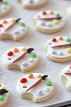 decorated sugar cookies with paintbrushes and buttons on the top one cookie has white icing