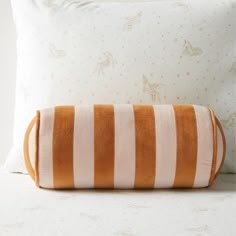 an orange and white striped pillow sitting on top of a bed