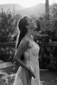 black and white photograph of a woman in a dress looking up at the sky with mountains in the background