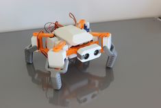 an orange and white robot sitting on top of a table