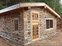 a small building made out of logs and wood with geometric designs on the door, windows and roof