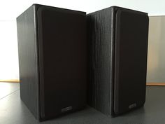 two black speakers sitting on top of a table