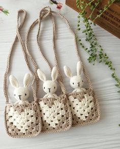 three crocheted bunny purses hanging on a table