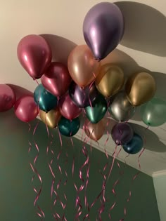 a bunch of balloons that are in the air with some pink and green streamers