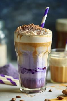 there is a drink with purple and white liquid in the glass next to some coffee beans