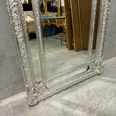 a large silver mirror sitting on top of a floor