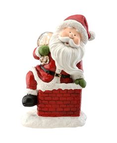 a santa clause figurine sitting on top of a brick wall