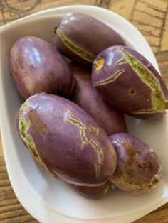 some purple potatoes in a white bowl on a wooden table