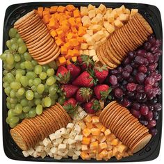 a platter filled with crackers, grapes, strawberries, and cheeses