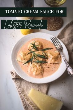 a white plate topped with ravioli covered in cream sauce and garnished with green herbs