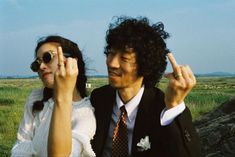 a man and woman standing next to each other with their fingers in the air as they look at something