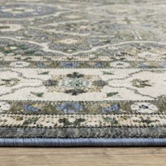 an area rug with blue and green flowers on the bottom, in front of a wooden floor