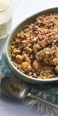 a bowl filled with granola and fruit on top of a blue towel next to a glass of milk