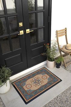 a black door with two chairs and a rug on the front porch next to it