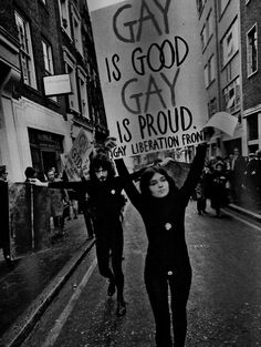 a woman holding up a sign while walking down the street with other people behind her