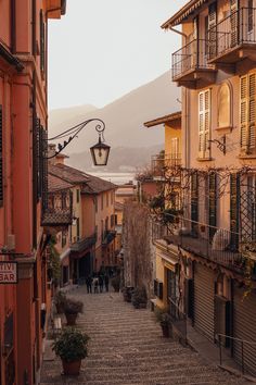 an alley way with people walking down it and buildings on both sides that have balconies